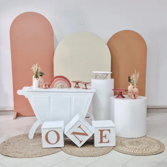 Set con cubos de letras, arcos en tonos tierra y mesa blanca